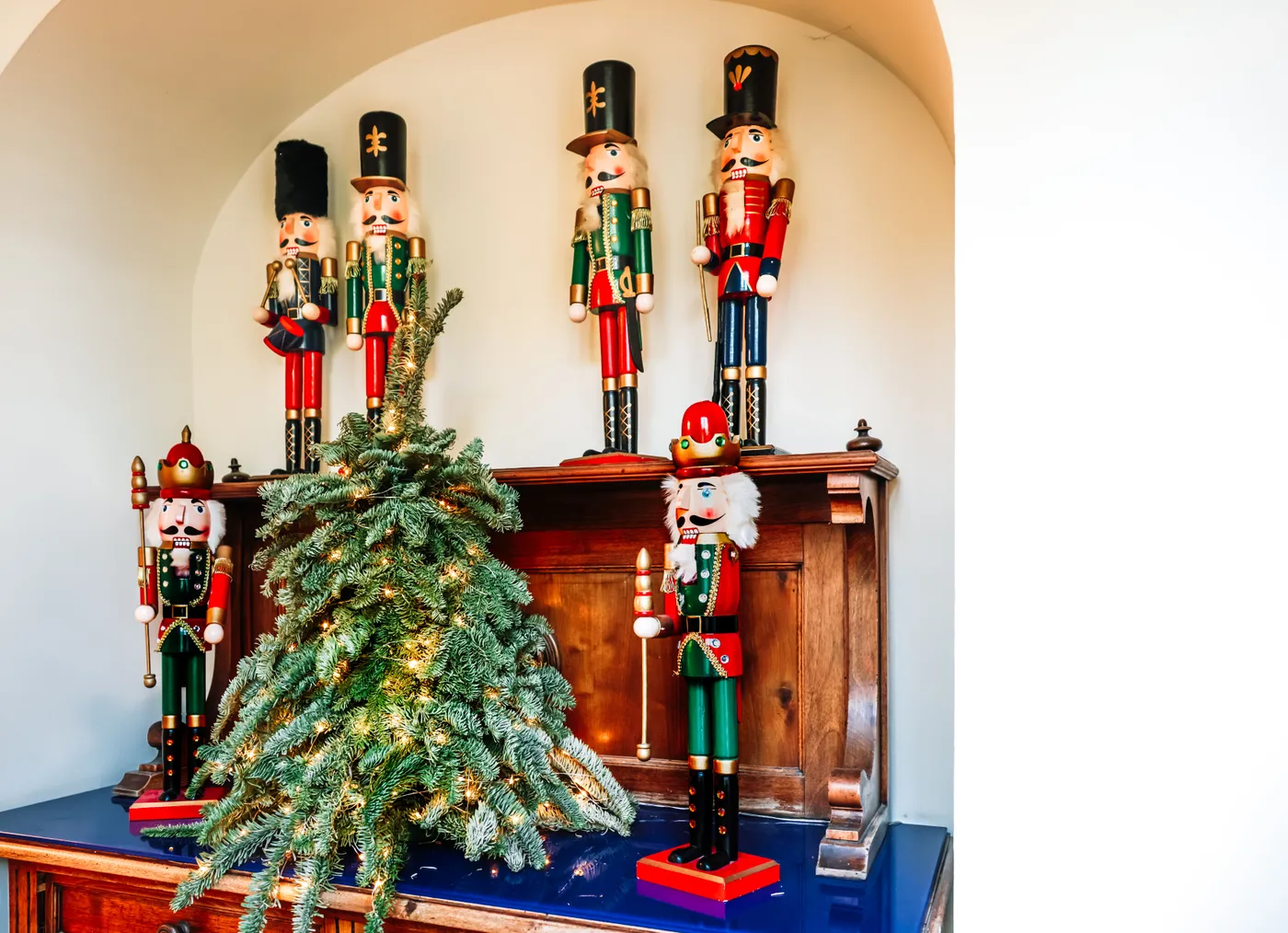 A collection of nutcracker figurines with a small Christmas tree creates a festive indoor holiday display.