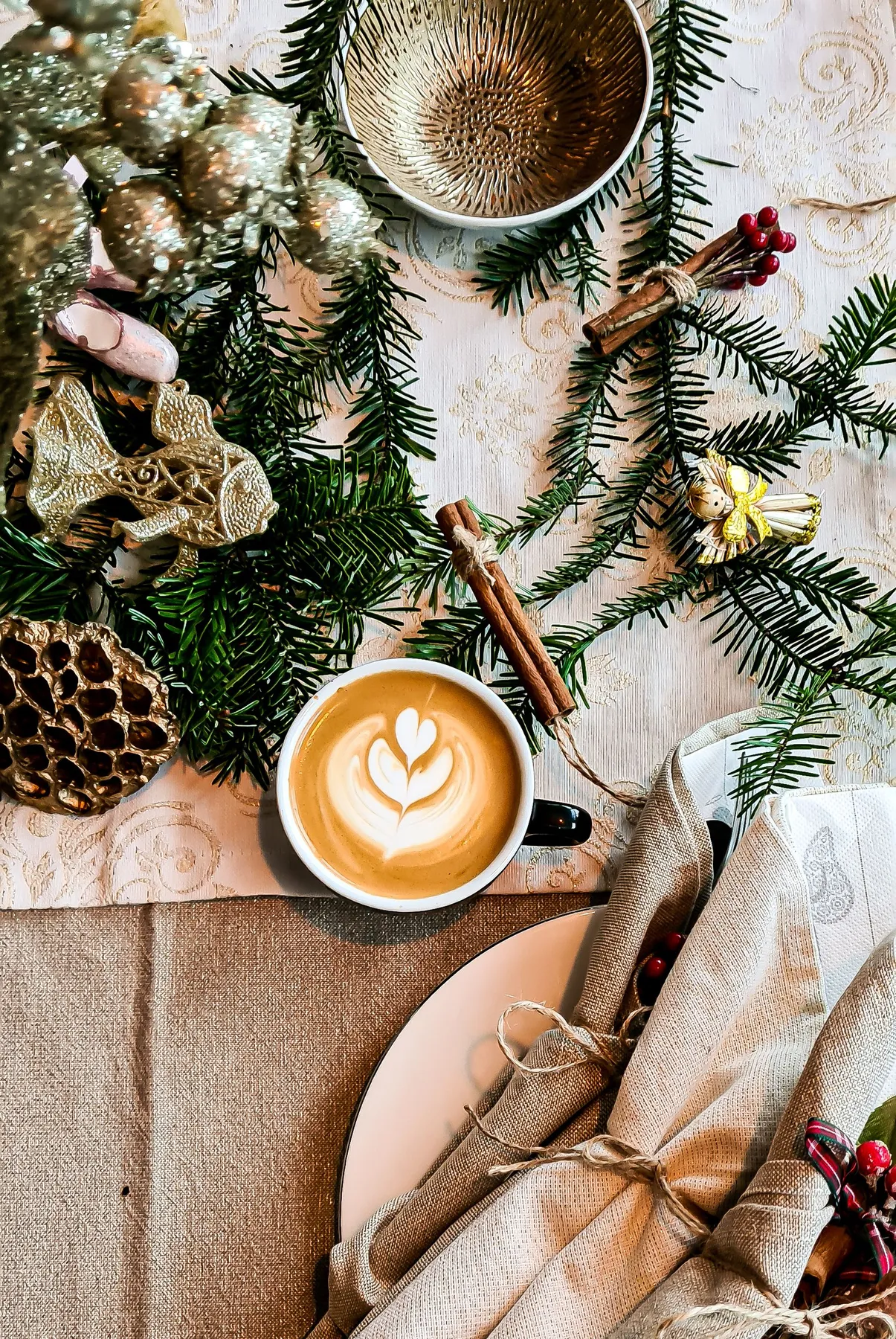 A cozy holiday setting featuring a cup of latte with Christmas decorations and greenery.