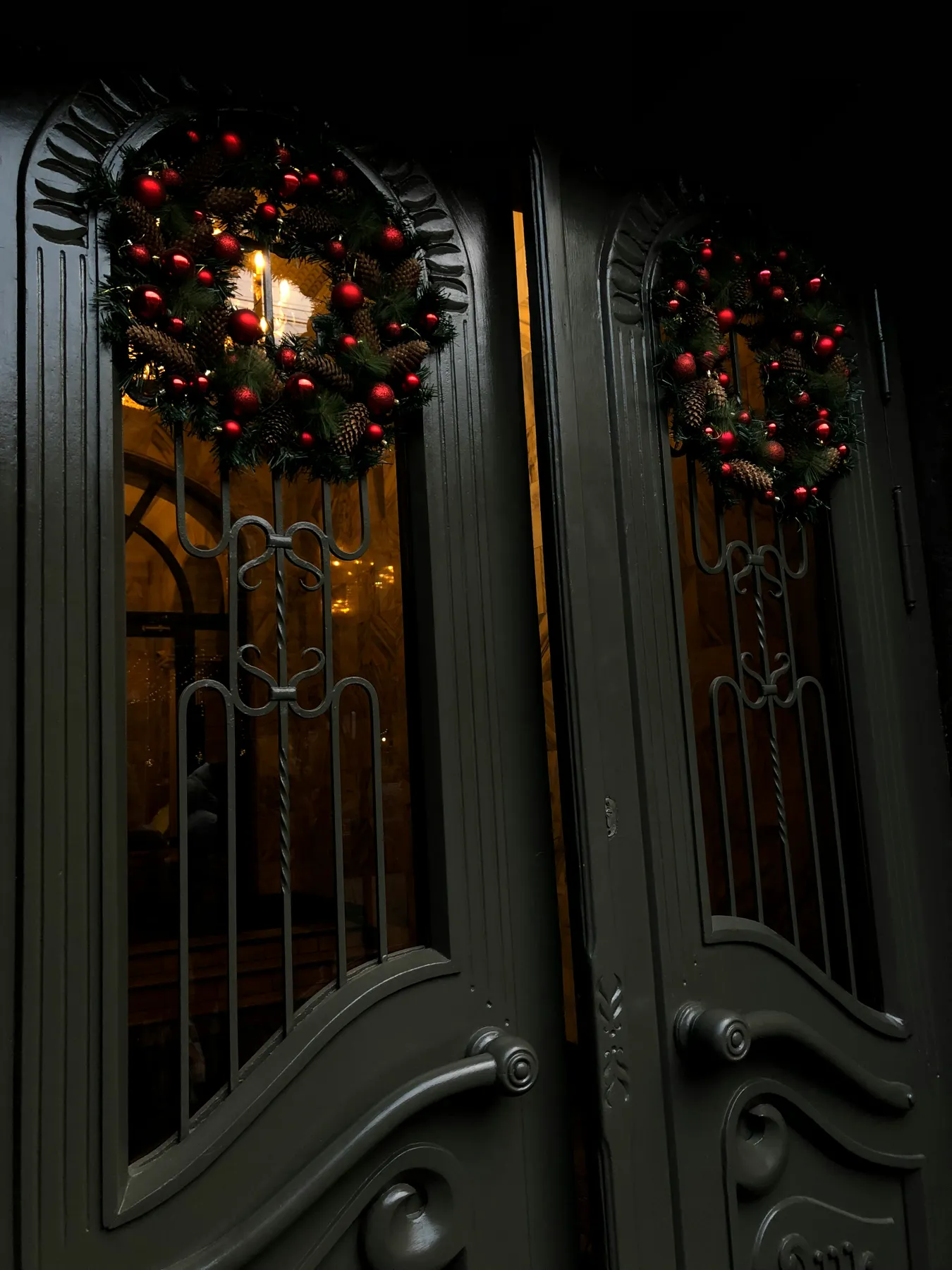 a pair of double doors decorated with christmas wreaths