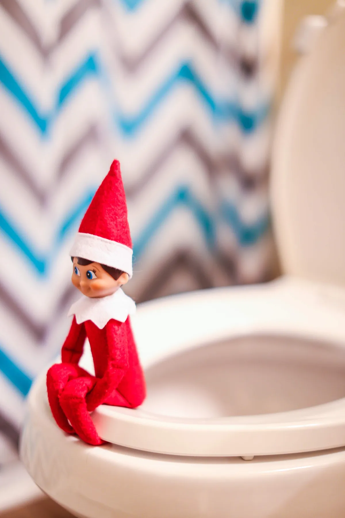 A whimsical elf figurine sits on a toilet seat, adding holiday charm indoors.