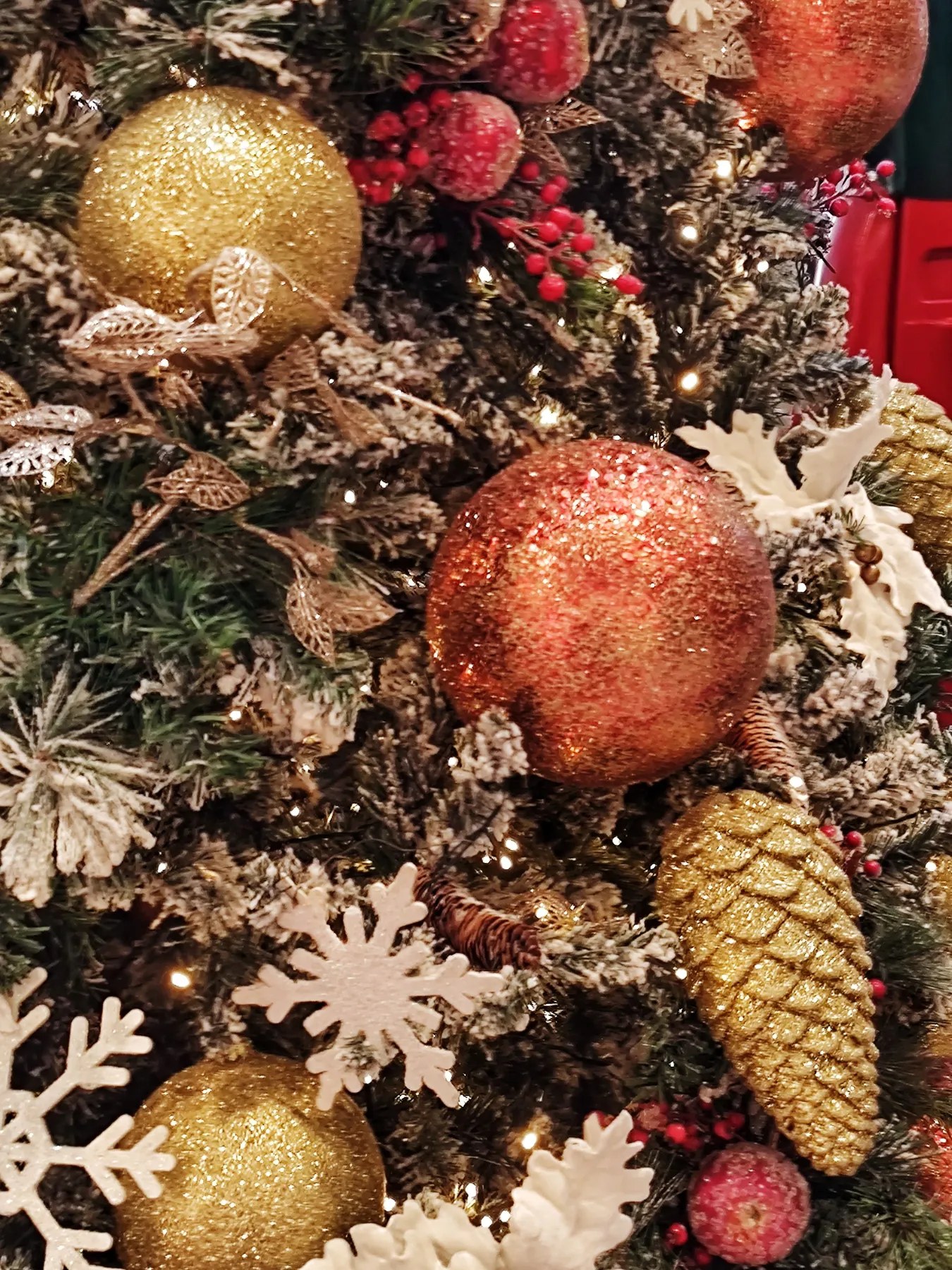 Beautifully decorated Christmas tree featuring golden ornaments, red berries, and snowflakes for a festive ambiance.