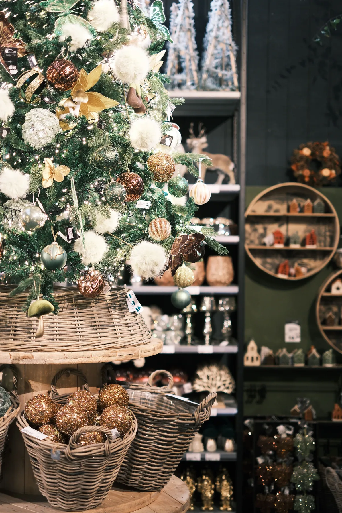 Beautifully decorated Christmas tree with ornaments in a festive shop setting.