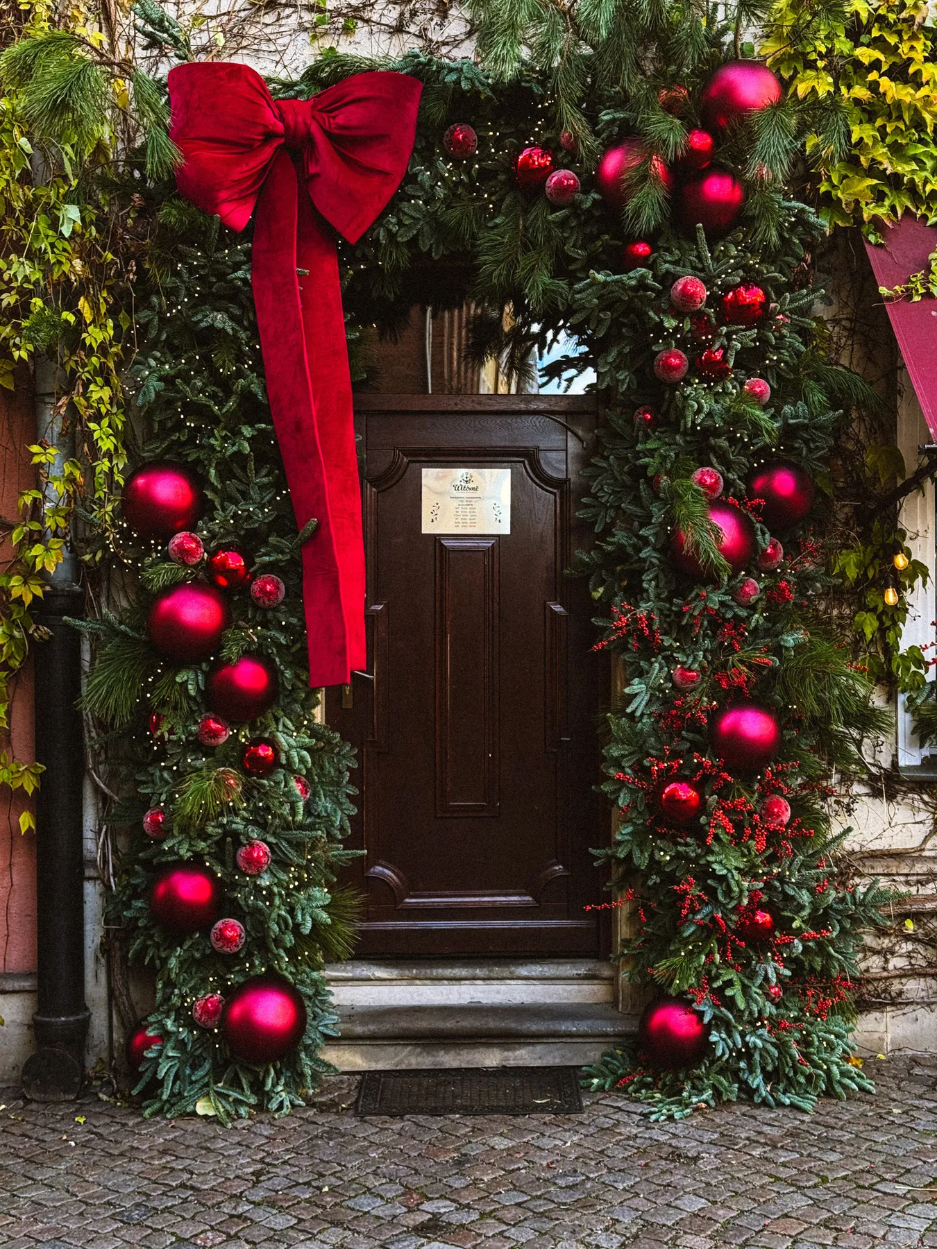 Charming Christmas doorway adorned with green garland and red bows.