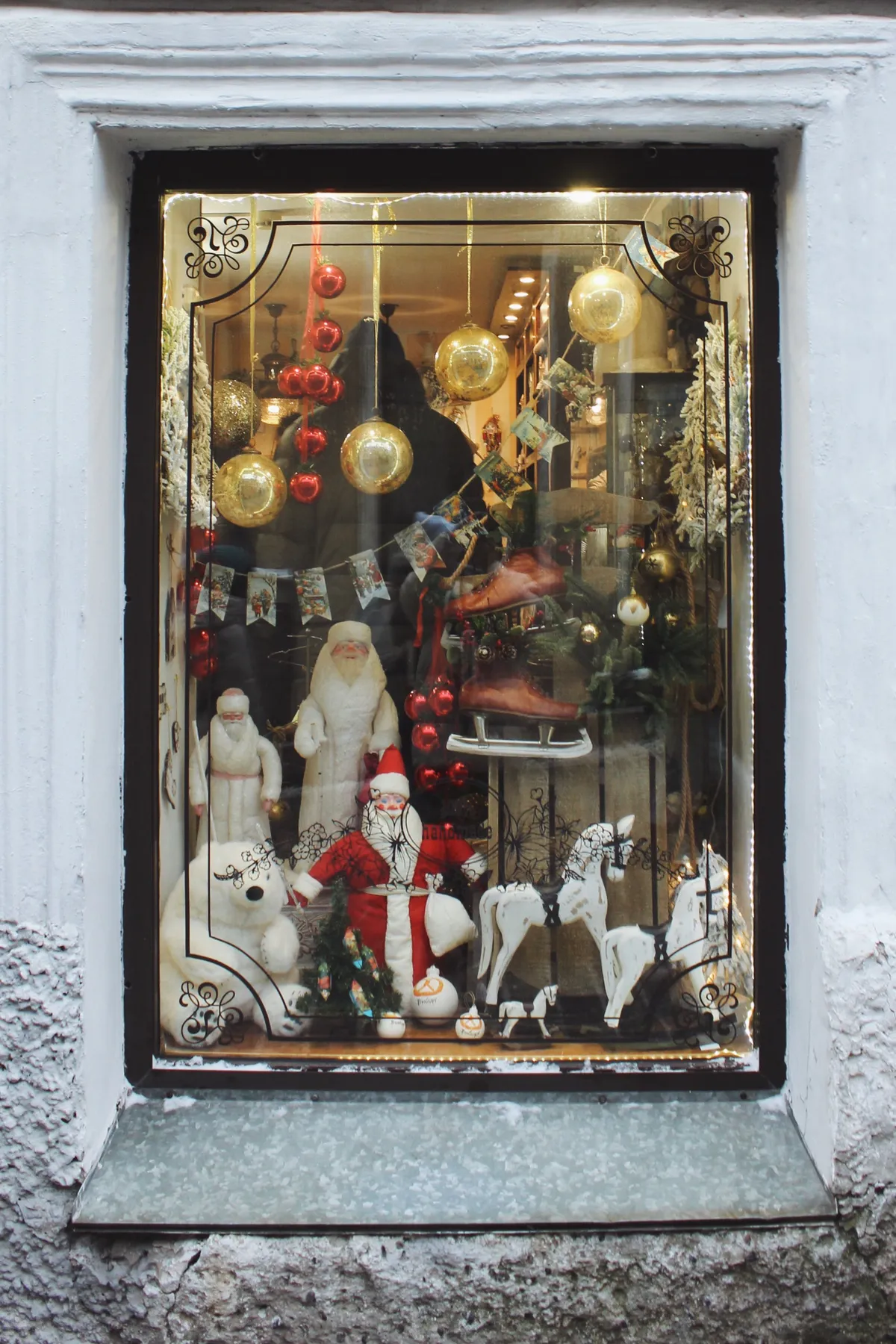 Charming Christmas window display featuring Santa figures, ornaments, and decorative items.