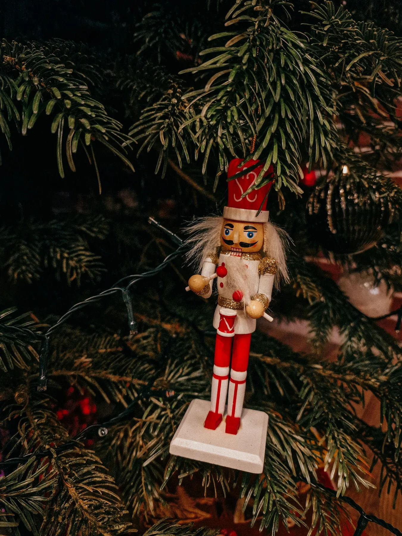 Charming nutcracker doll hanging on a Christmas tree branch, creating a festive holiday ambiance.