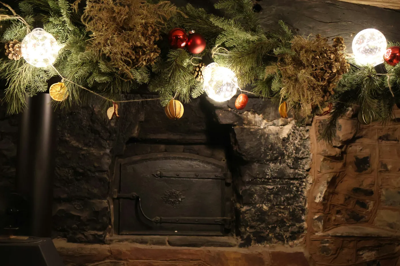 Christmas garland with lights above a rustic fireplace