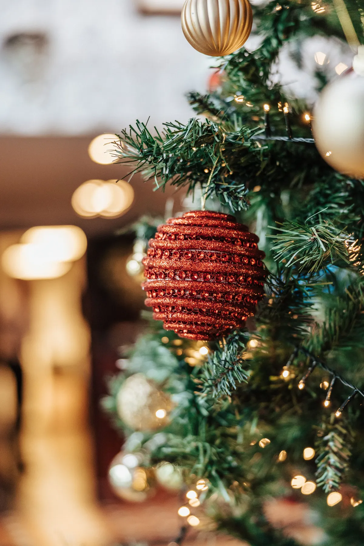 Close-up of a Christmas tree decorated with a red bauble and golden ornaments, capturing holiday spirit indoors.