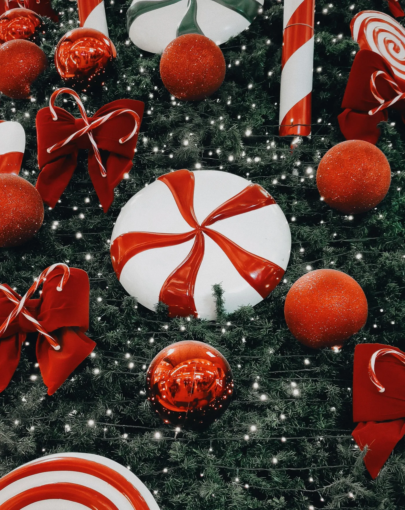 Close-up of a Christmas tree with red and white ornaments, candy canes, and lights, capturing festive holiday spirit.