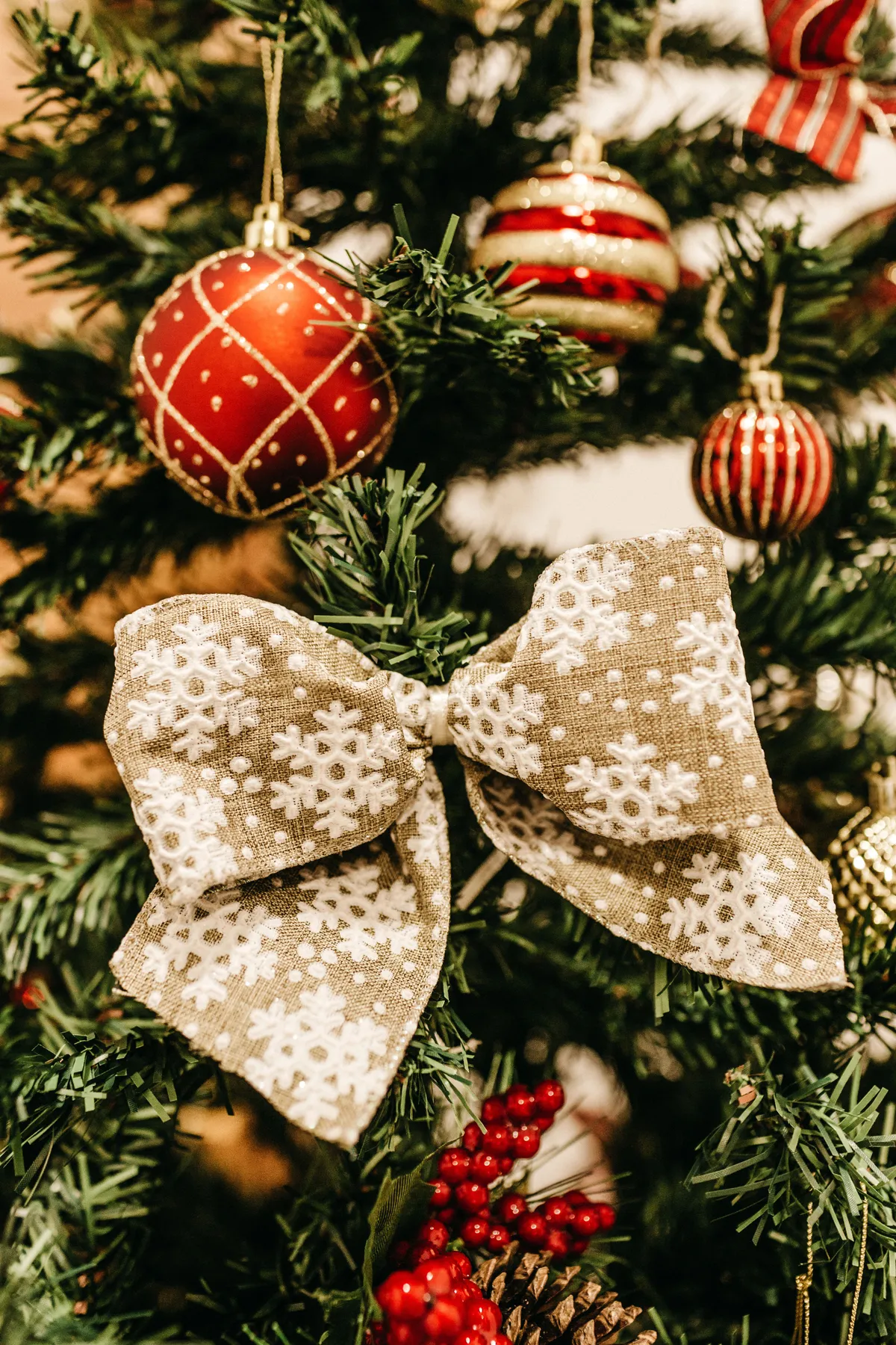 Close-up of a decorated Christmas tree featuring ornaments, a large bow, and lush greenery.