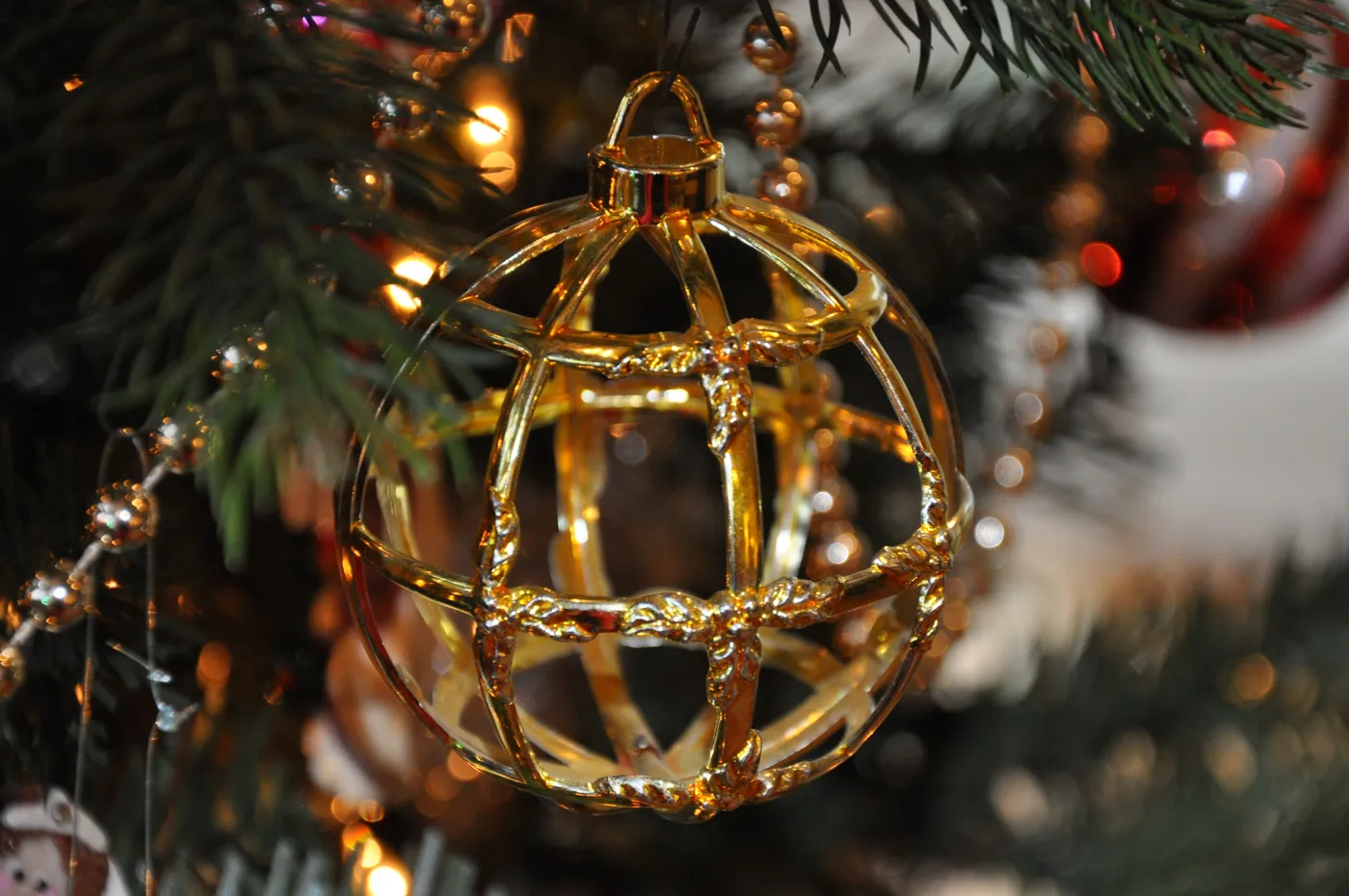 Close-up of a gold Christmas ornament hanging on a tree, symbolizing festive holiday decor.