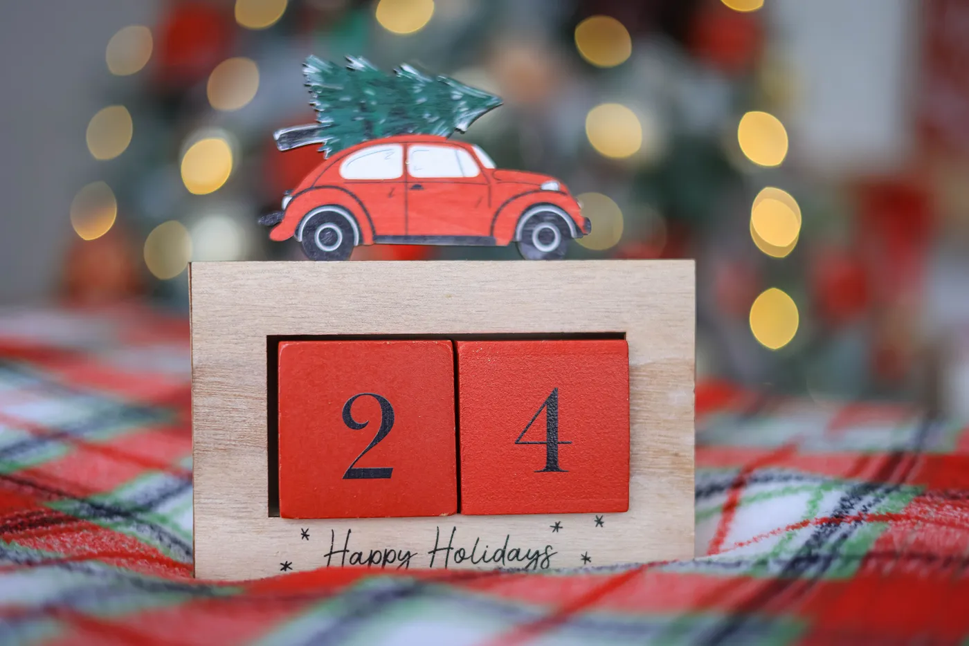 Close-up of a holiday ornament featuring a vintage car carrying a tree, surrounded by festive lights.