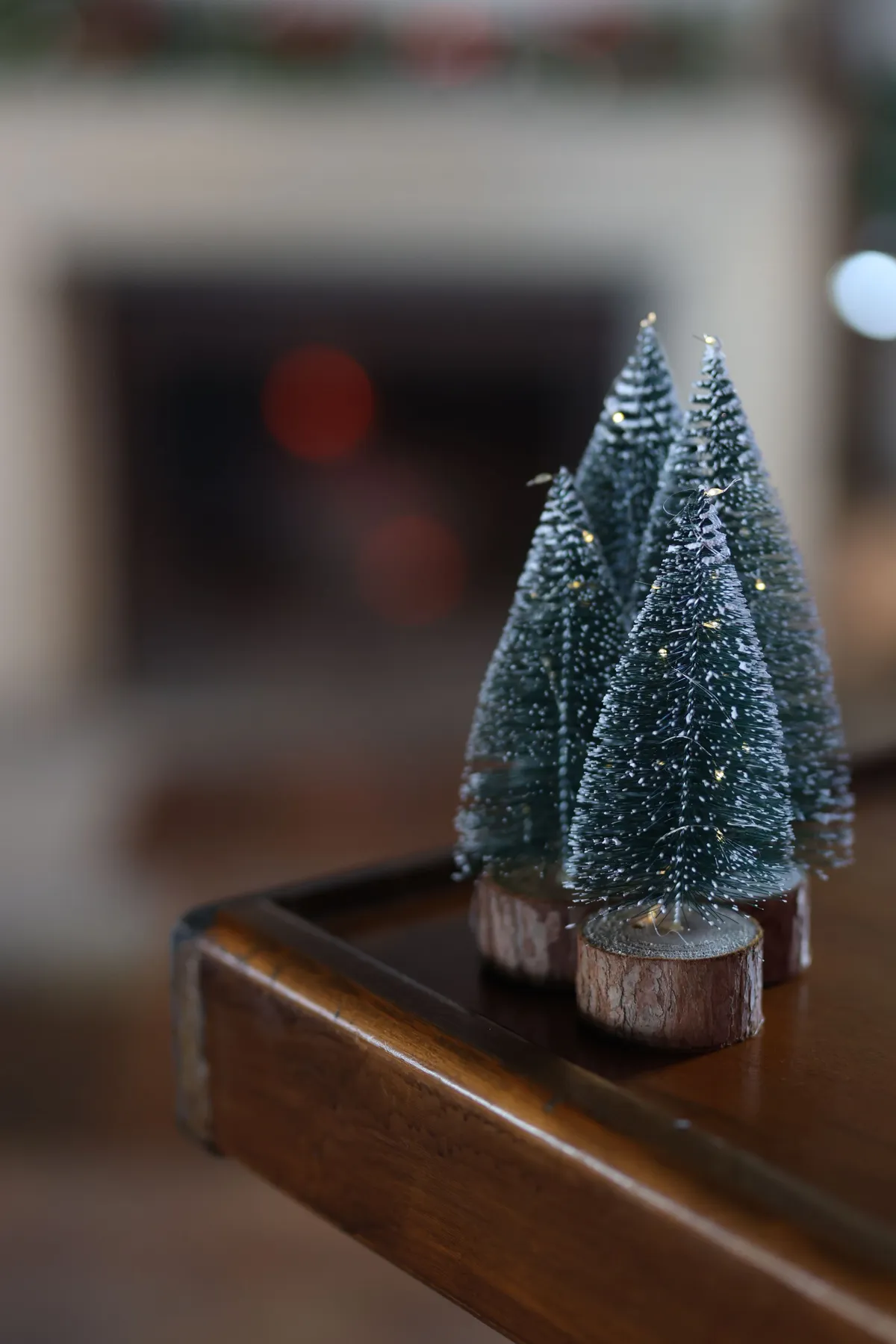 Close-up of mini decorative Christmas trees on a wooden table indoors, festive and cozy atmosphere.