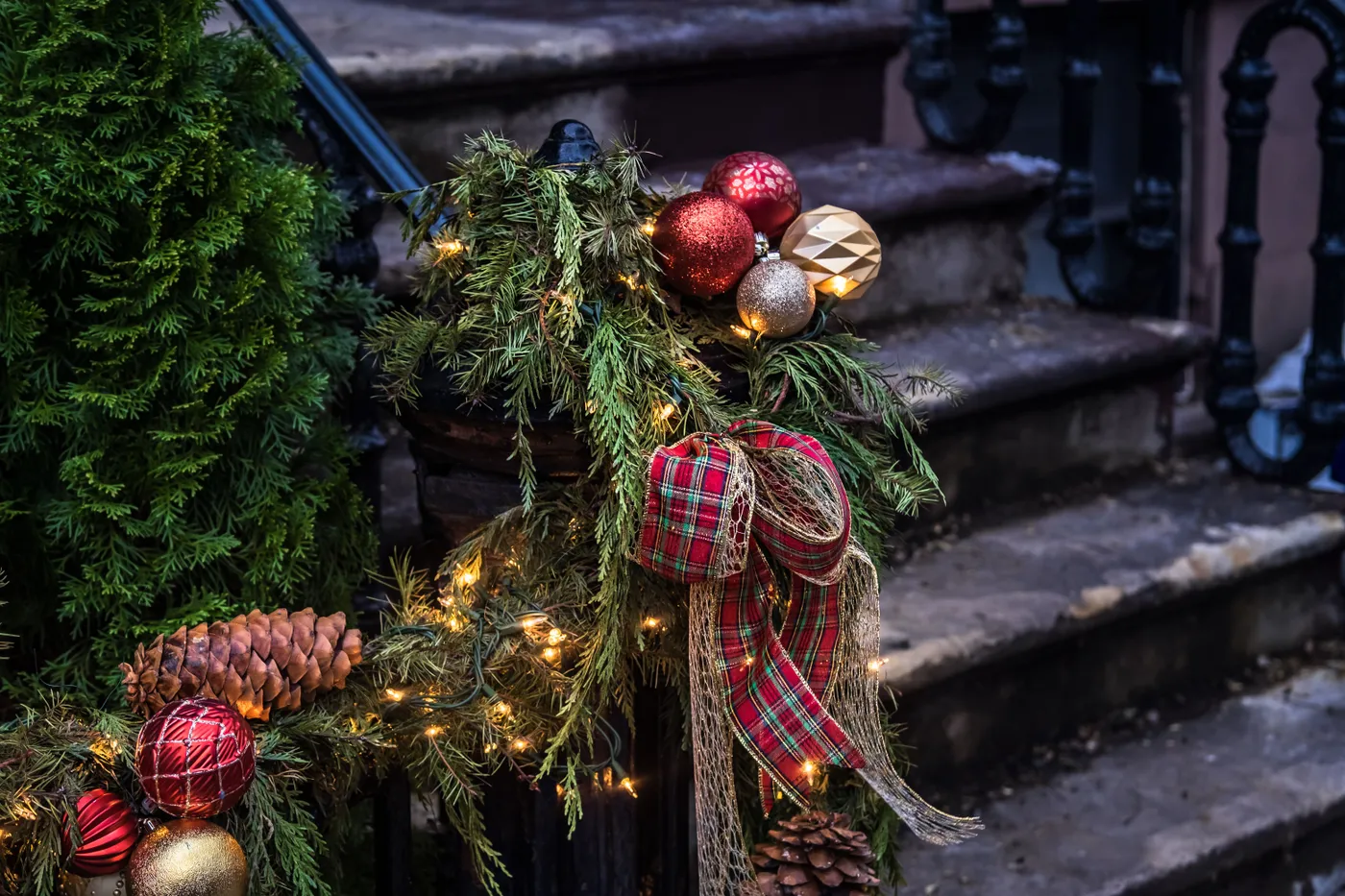 Colorful Christmas decorations with lights and greenery on outdoor stairs, creating a festive atmosphere.