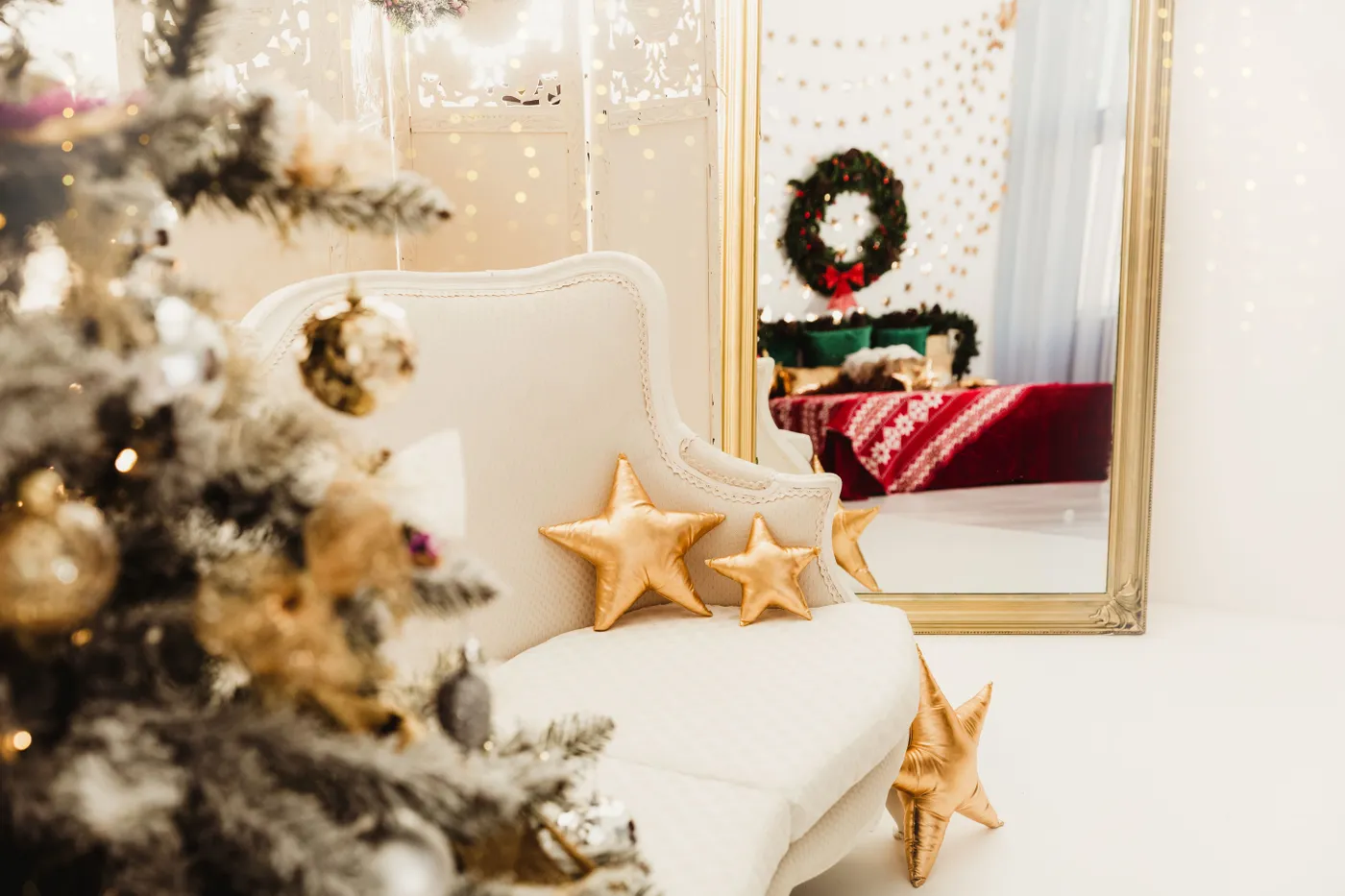 Cozy Christmas interior featuring a decorated tree, star pillows, and a festive mirror reflection.