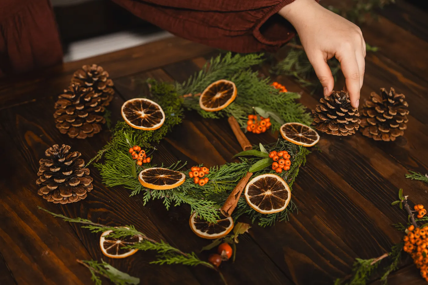 Create a festive wreath with pinecones, dried oranges, and berries for Christmas decor.