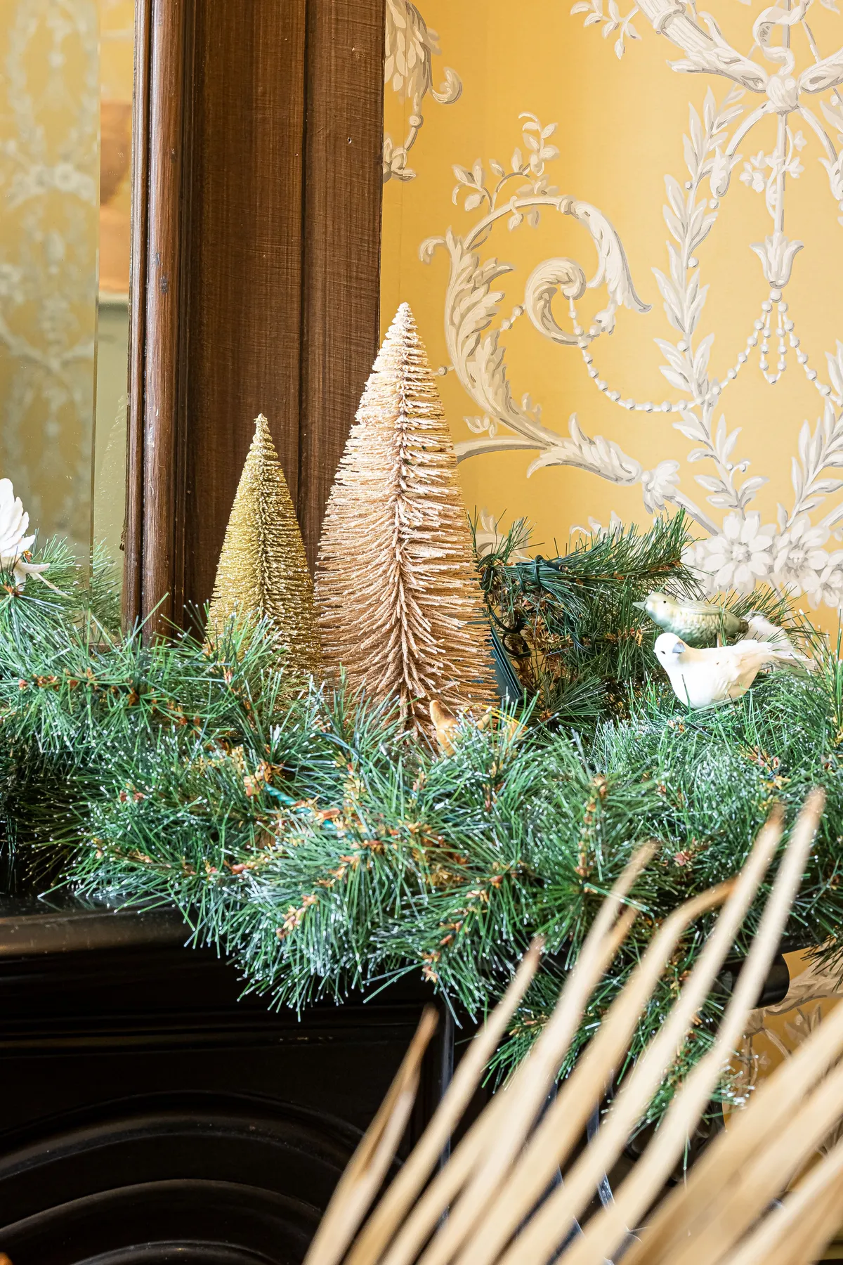 Elegant Christmas decor with conifer branches and festive ornaments on a mantelpiece.
