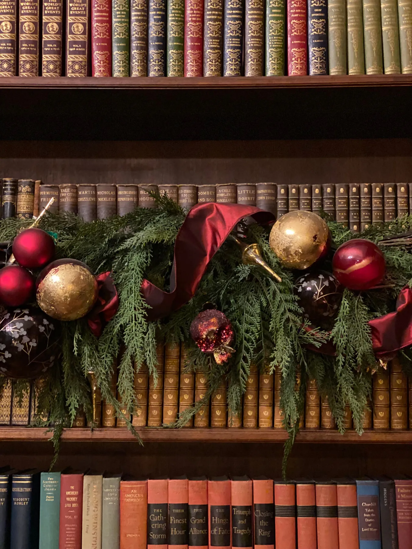 Elegant Christmas garland with ornaments draped over a vintage bookshelf. Cozy holiday decor.