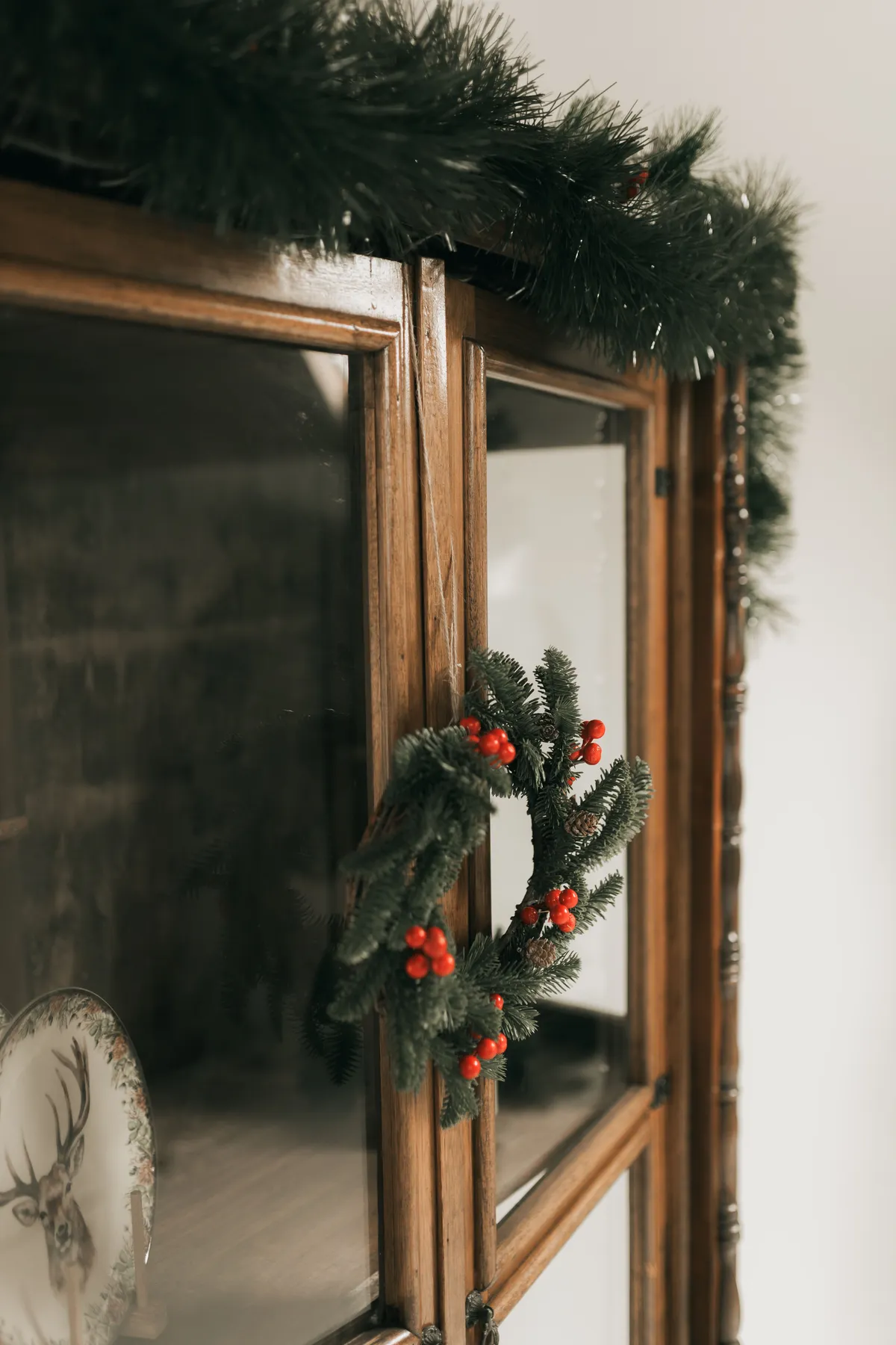 Elegant Christmas wreath decoration on wooden cabinet with seasonal greenery.