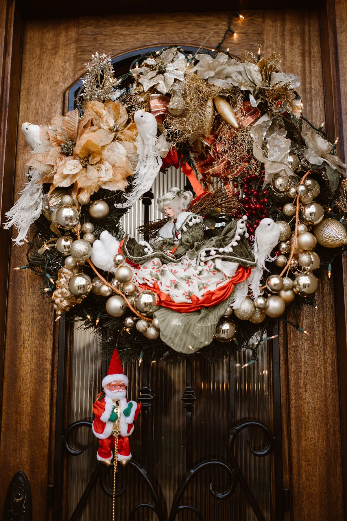 Elegant festive wreath with Santa and decorations on a wooden door, perfect for holiday cheer.