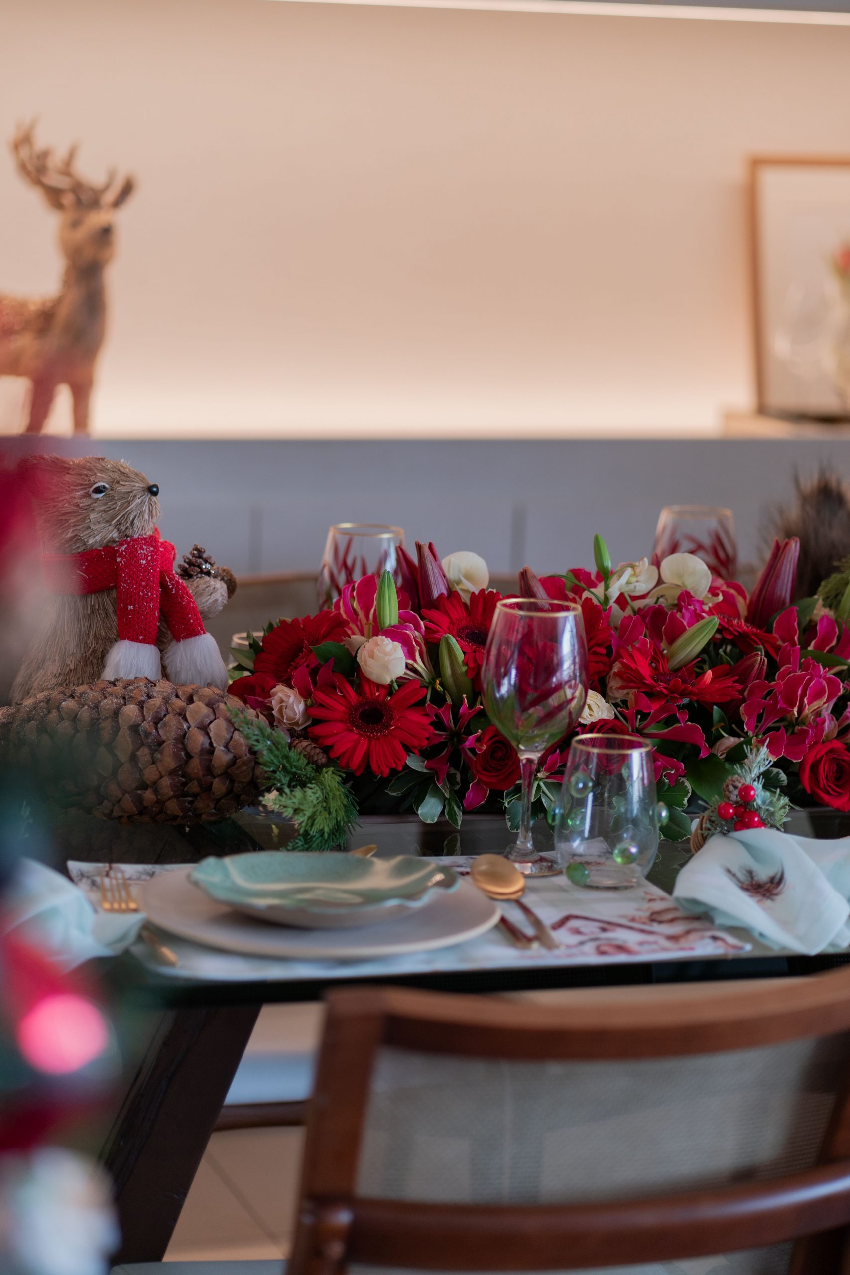 Elegant holiday dining table decorated with red flowers and festive ornaments.