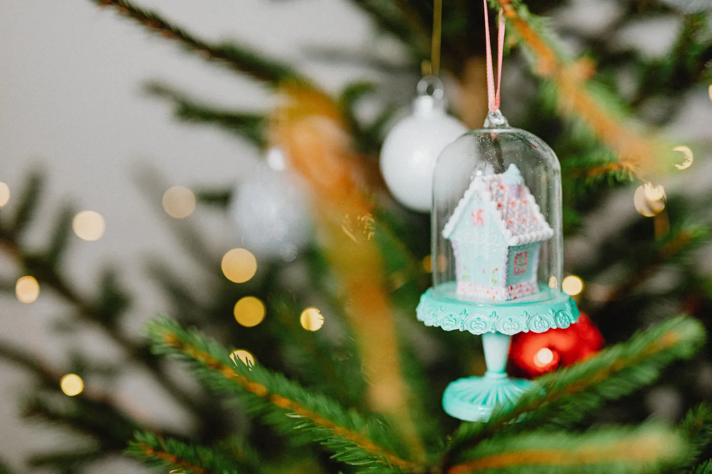 Enchanting gingerbread house ornament on Christmas tree with bokeh lights.