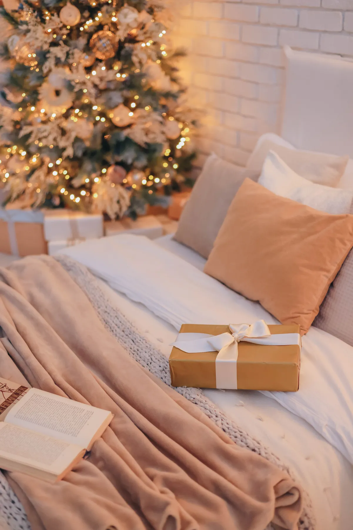 Festive bedroom scene with a Christmas tree, gift, and cozy bedding, highlighting holiday warmth.