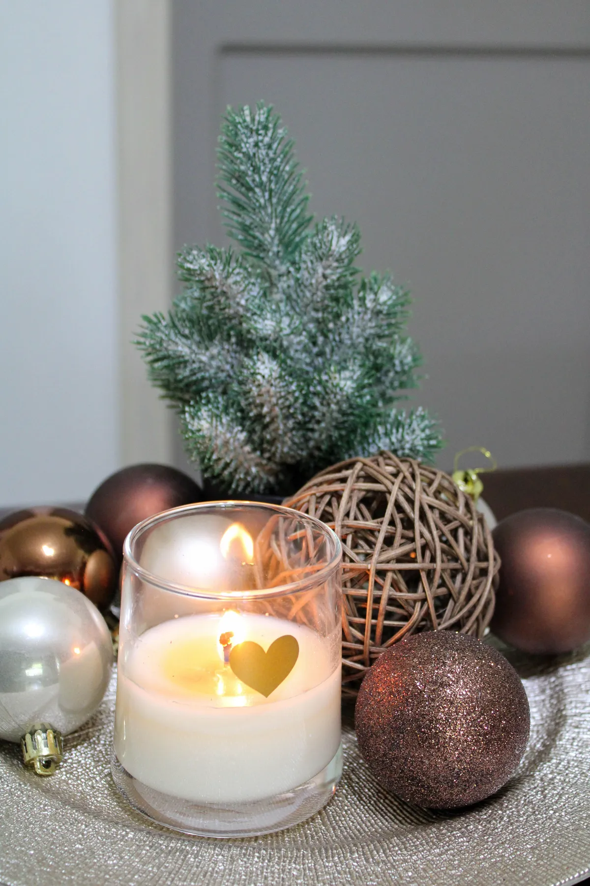 Festive candle and Christmas ornaments with a small snow-dusted tree.