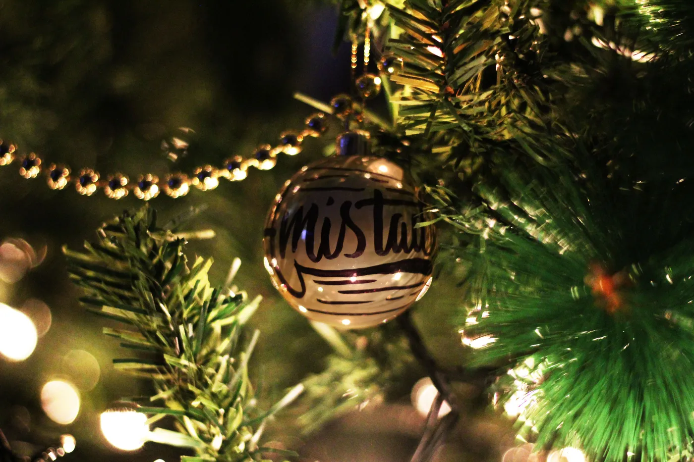 Festive Christmas ornament hanging on a decorated tree with lights.