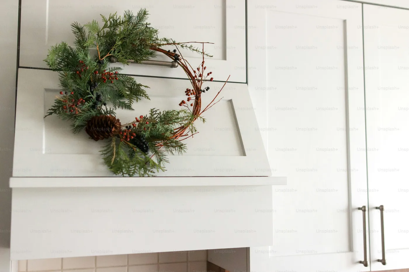 Festive wreath on white kitchen cabinets - Photo on Unsplash+