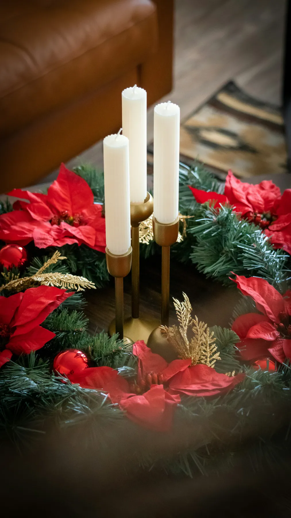 Gold candles on coffee table with poinsettia wreath for Christmas holiday. (IG@attimothyjames)