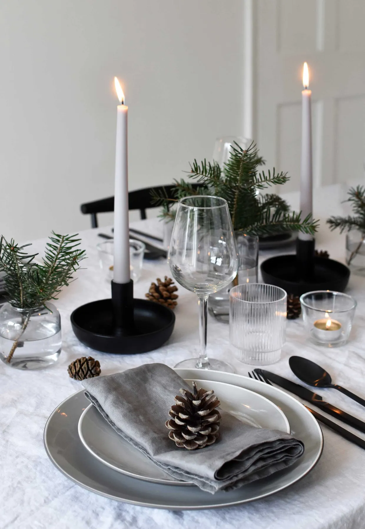 Minimalist Christmas table styling with fir, candles & pine cones |