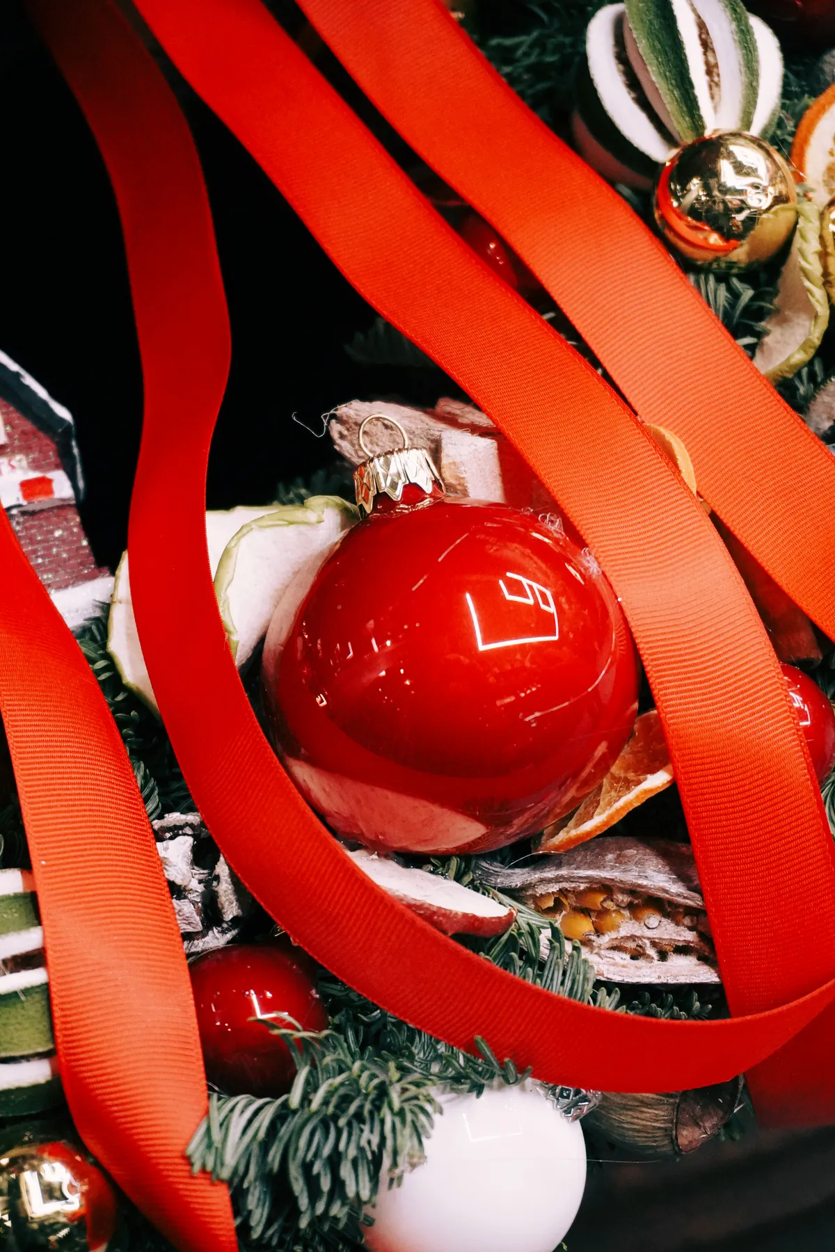 Red Christmas ornament on a display with red ribbons