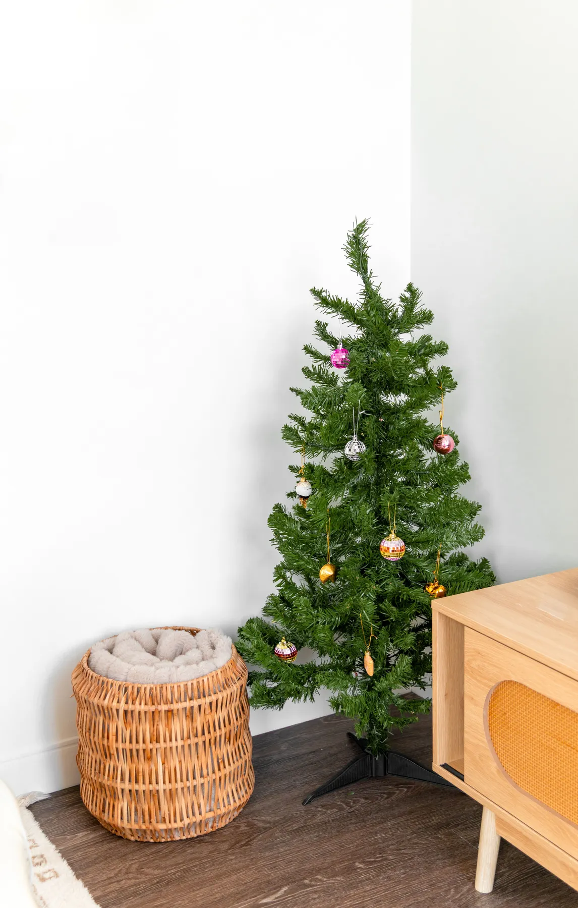 Small Christmas tree decorated with ornaments in a cozy indoor setting, perfect for minimalist holiday styling.
