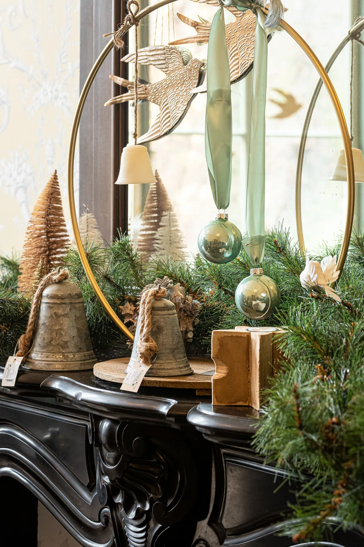 Stylish Christmas decorations with bells and ornaments on a mantelpiece.
