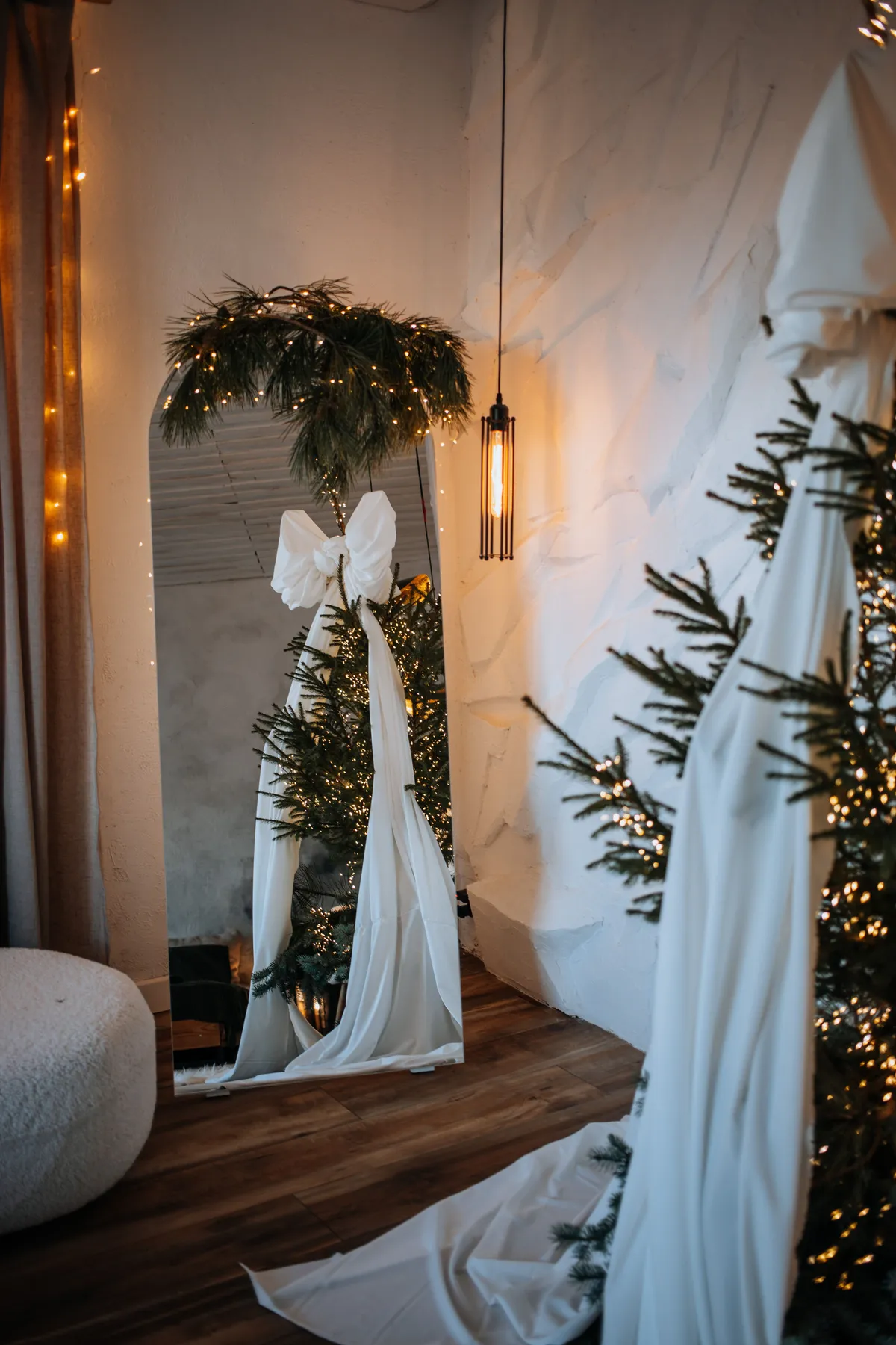 Stylish Christmas tree setup with modern decor and mirror reflection indoors.