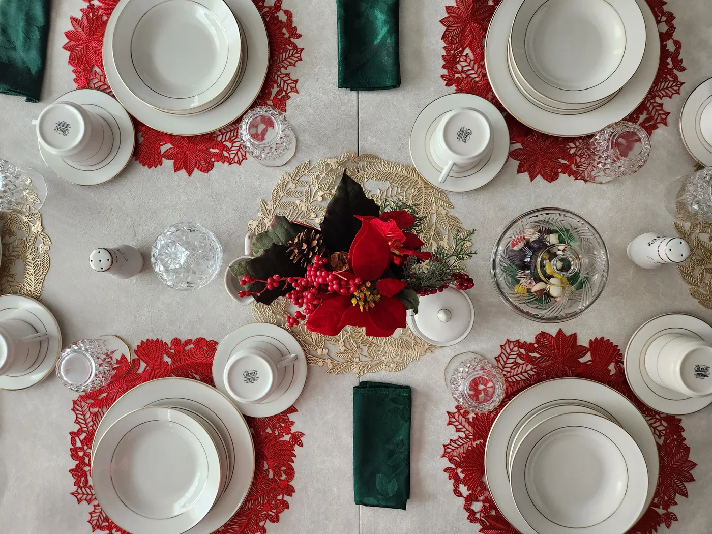 Top view of a beautifully set Christmas dinner table with porcelain plates and a vibrant floral centerpiece.
