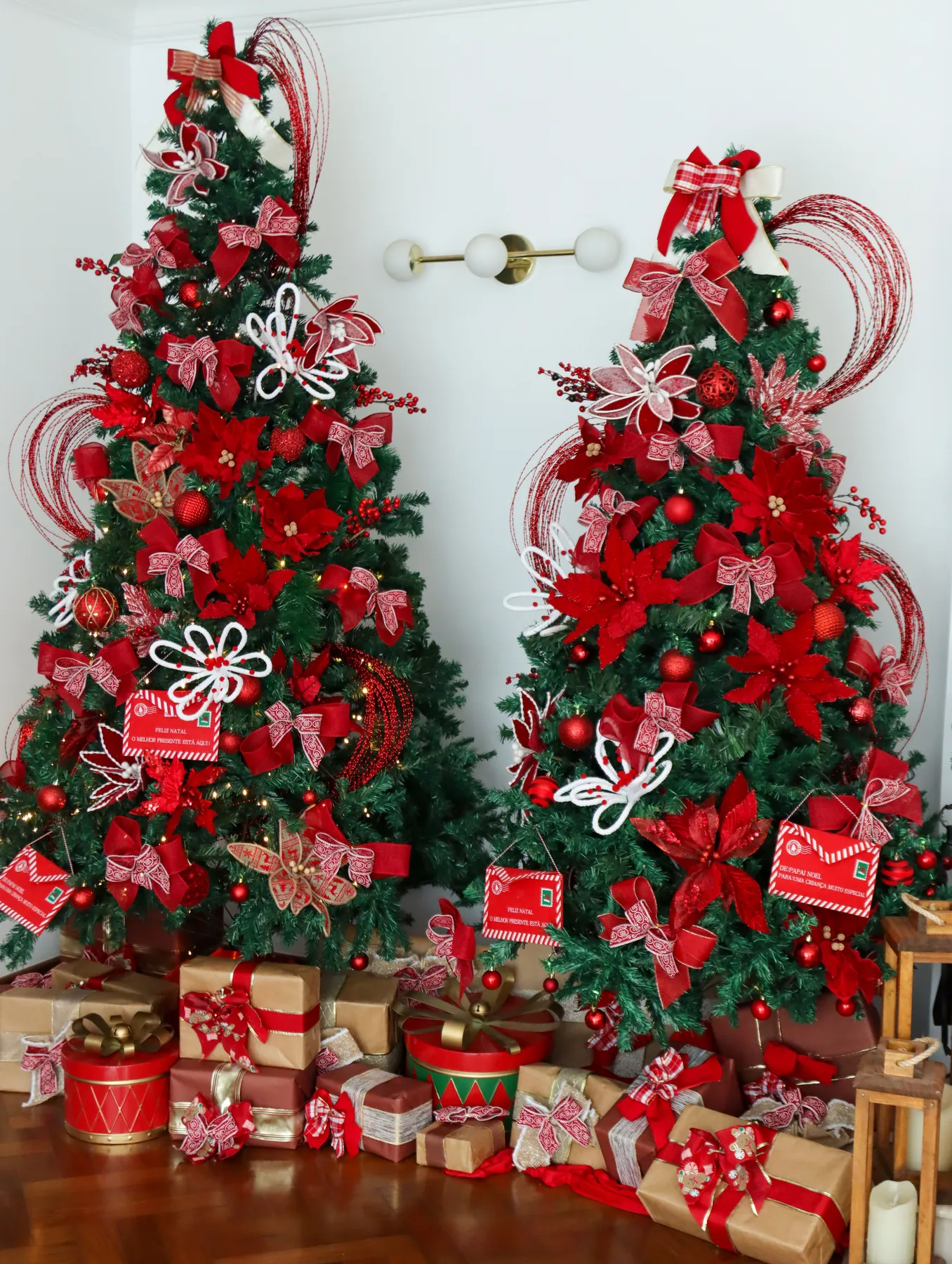 Two Christmas trees adorned with red ornaments and presents underneath.