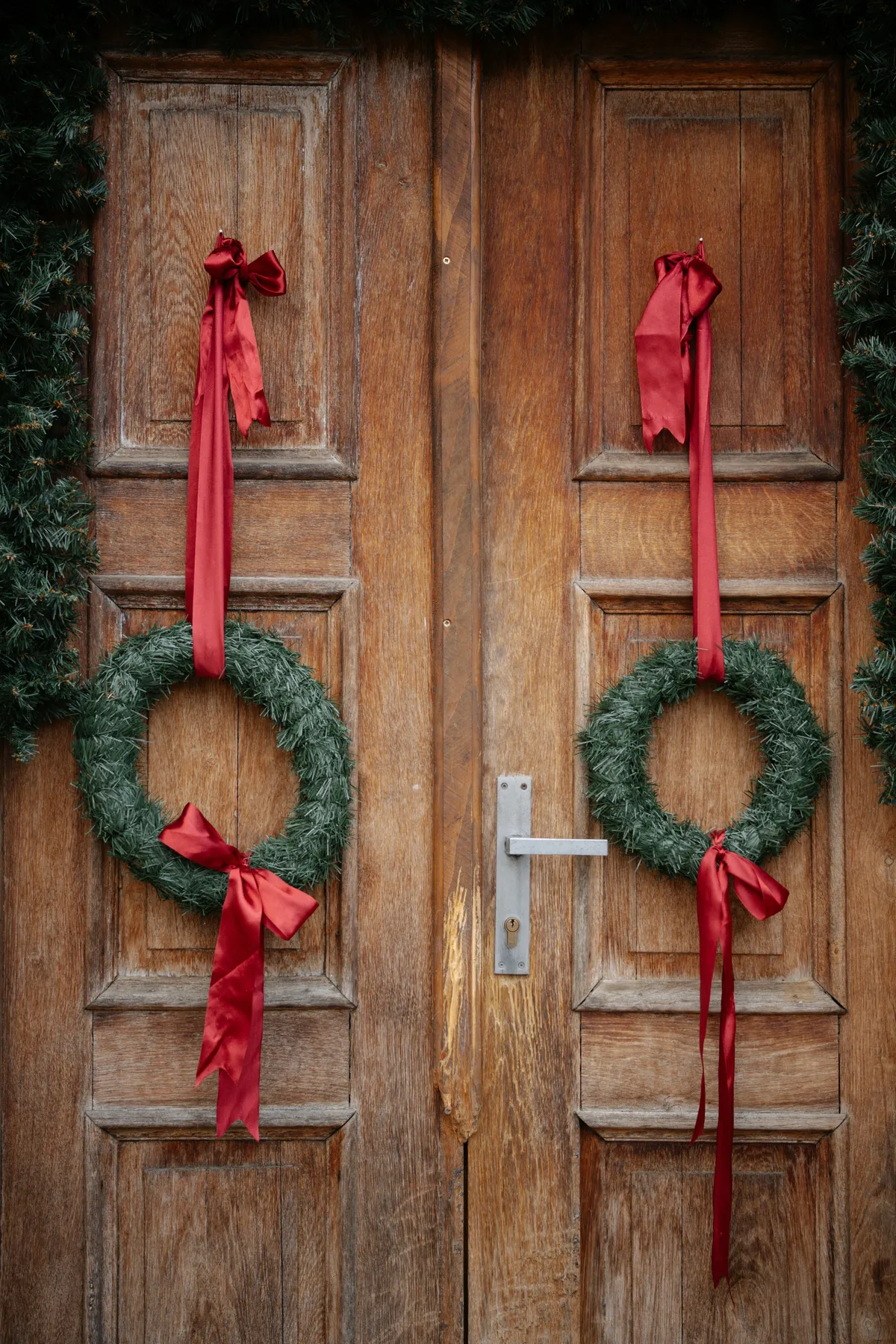 Two christmas wreaths hang on a wooden door