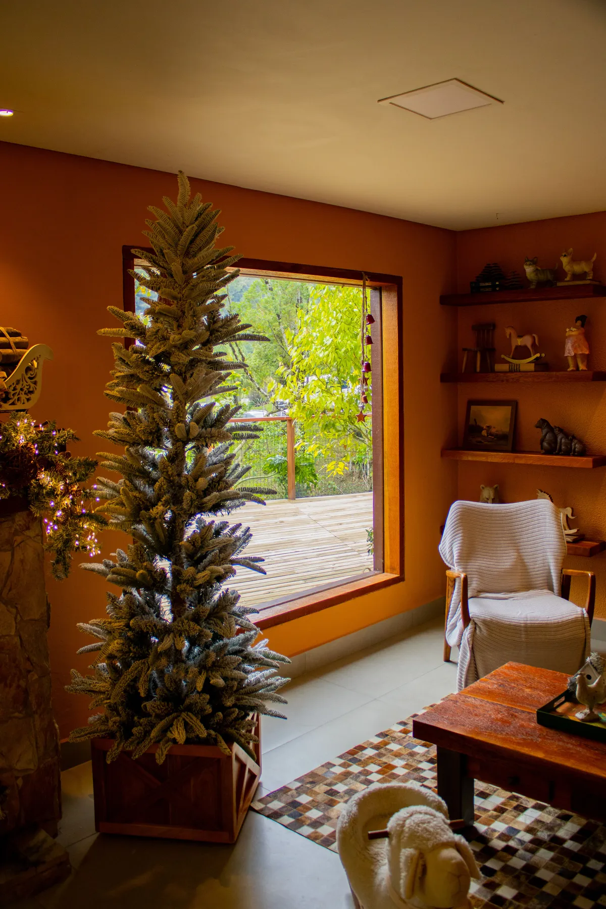 Warm and cozy living room with a decorated snowy Christmas tree by a large window.