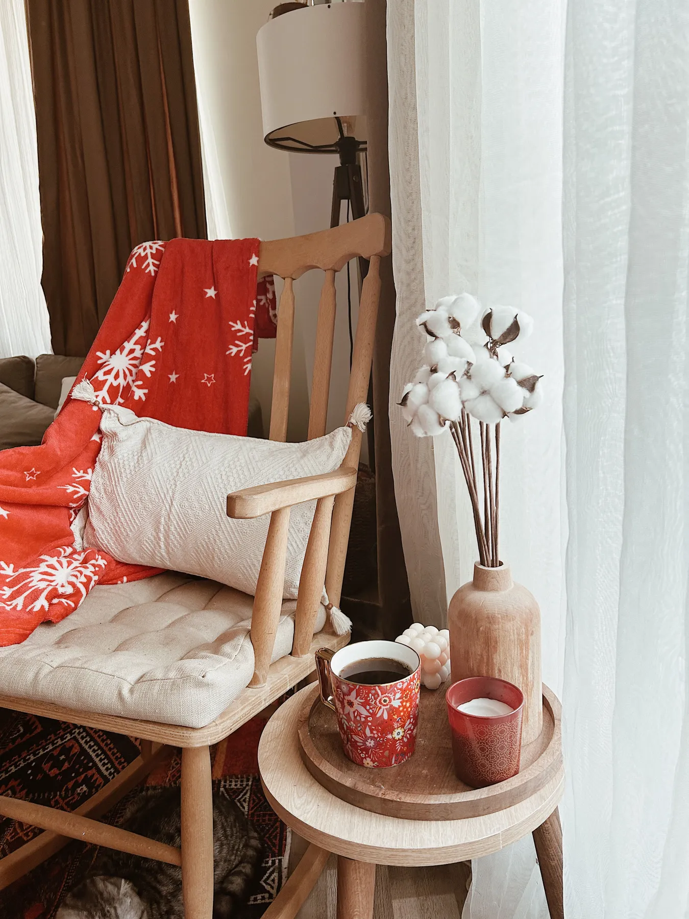 Warm and inviting home decor featuring a cozy armchair, red blanket, and decorative textiles.