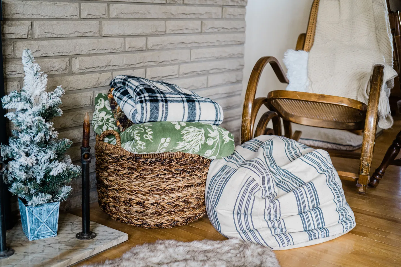 Warm and inviting home interior featuring blankets, a rocking chair, and a Christmas tree.