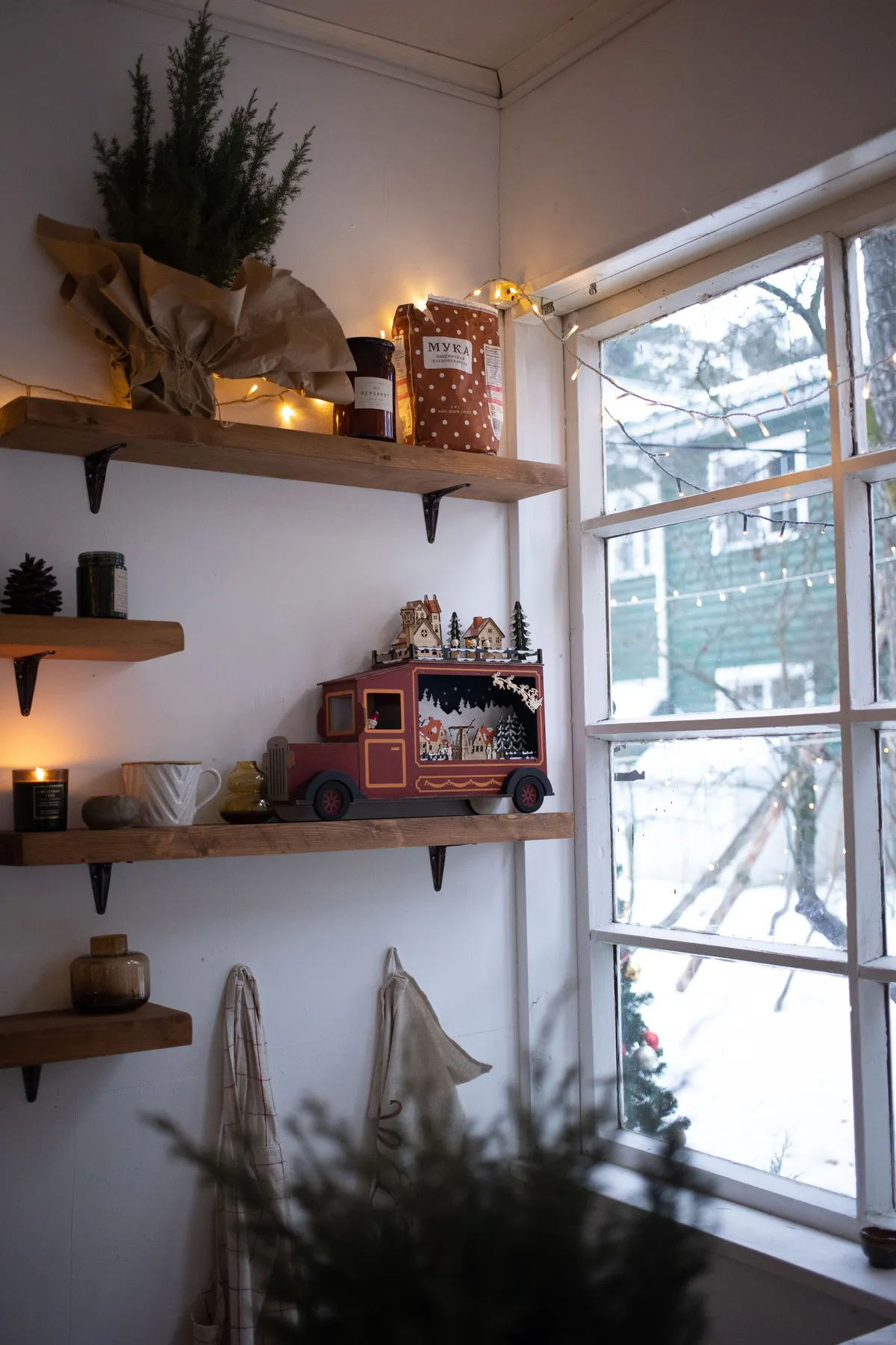 Warm and inviting indoor Christmas setting with rustic décor and snowy view.