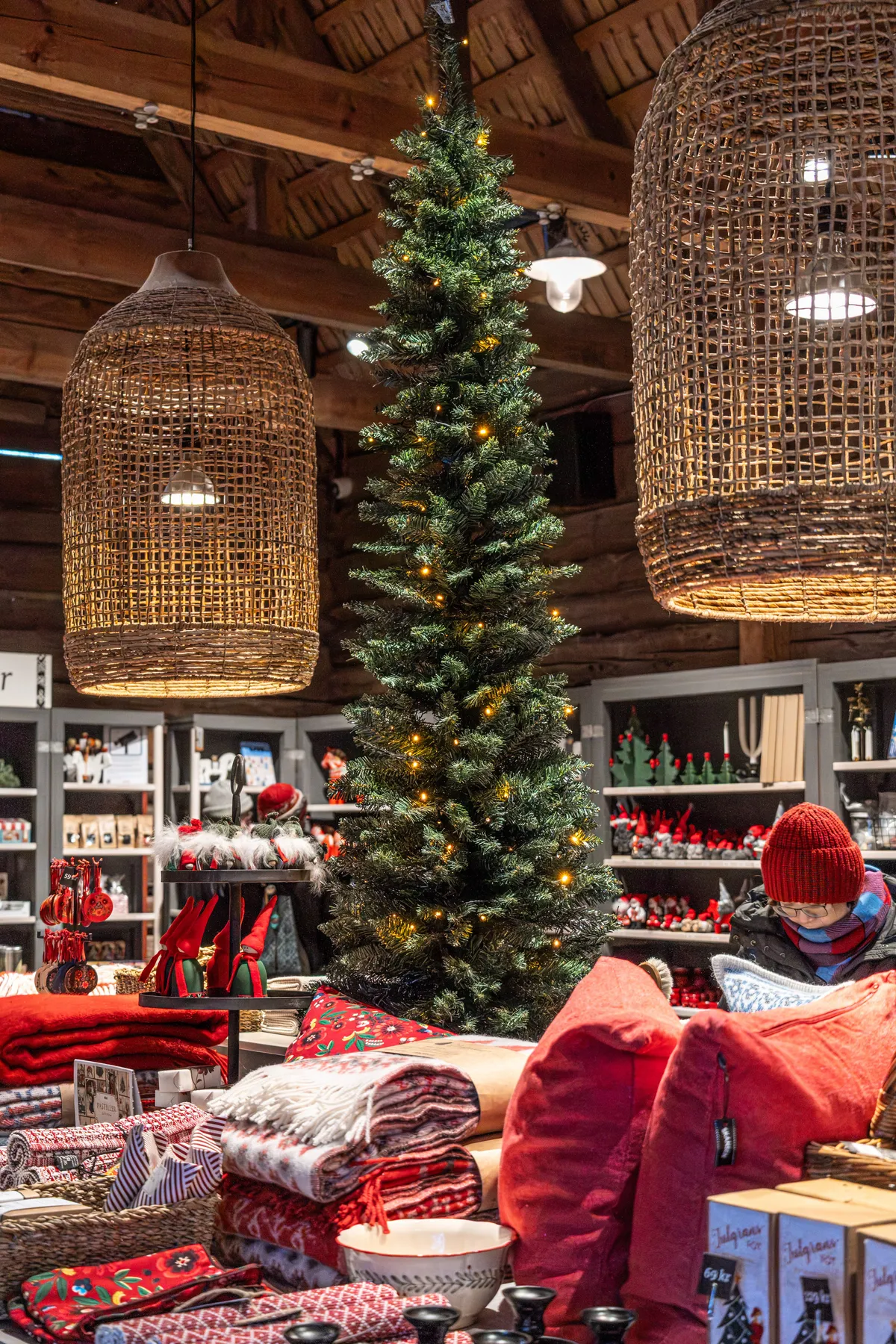 Warm interior of a boutique with festive decorations, a tall Christmas tree, and holiday merchandise.