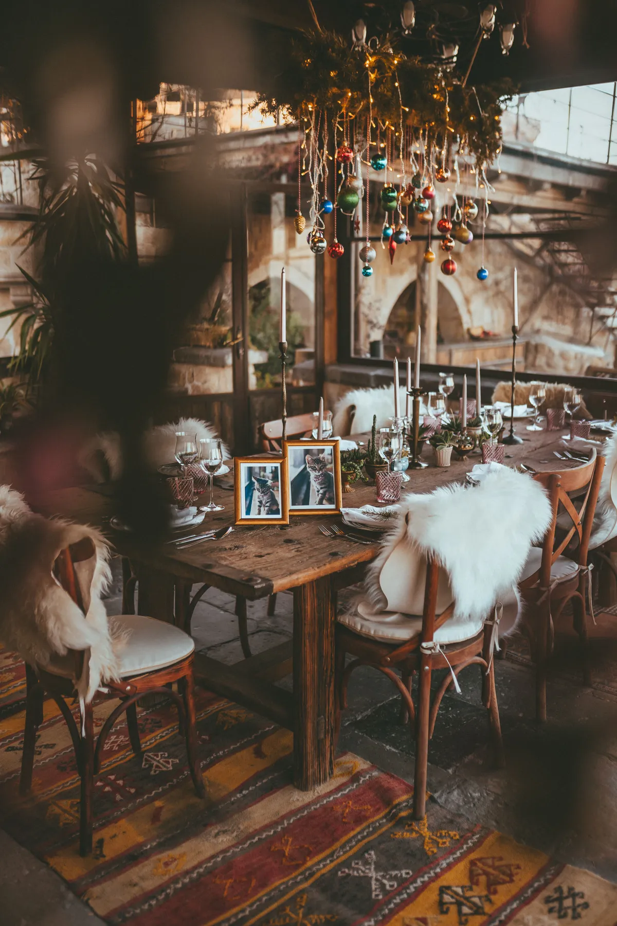 Warm rustic dining setup with holiday decor and fur chairs, perfect for festive gatherings.